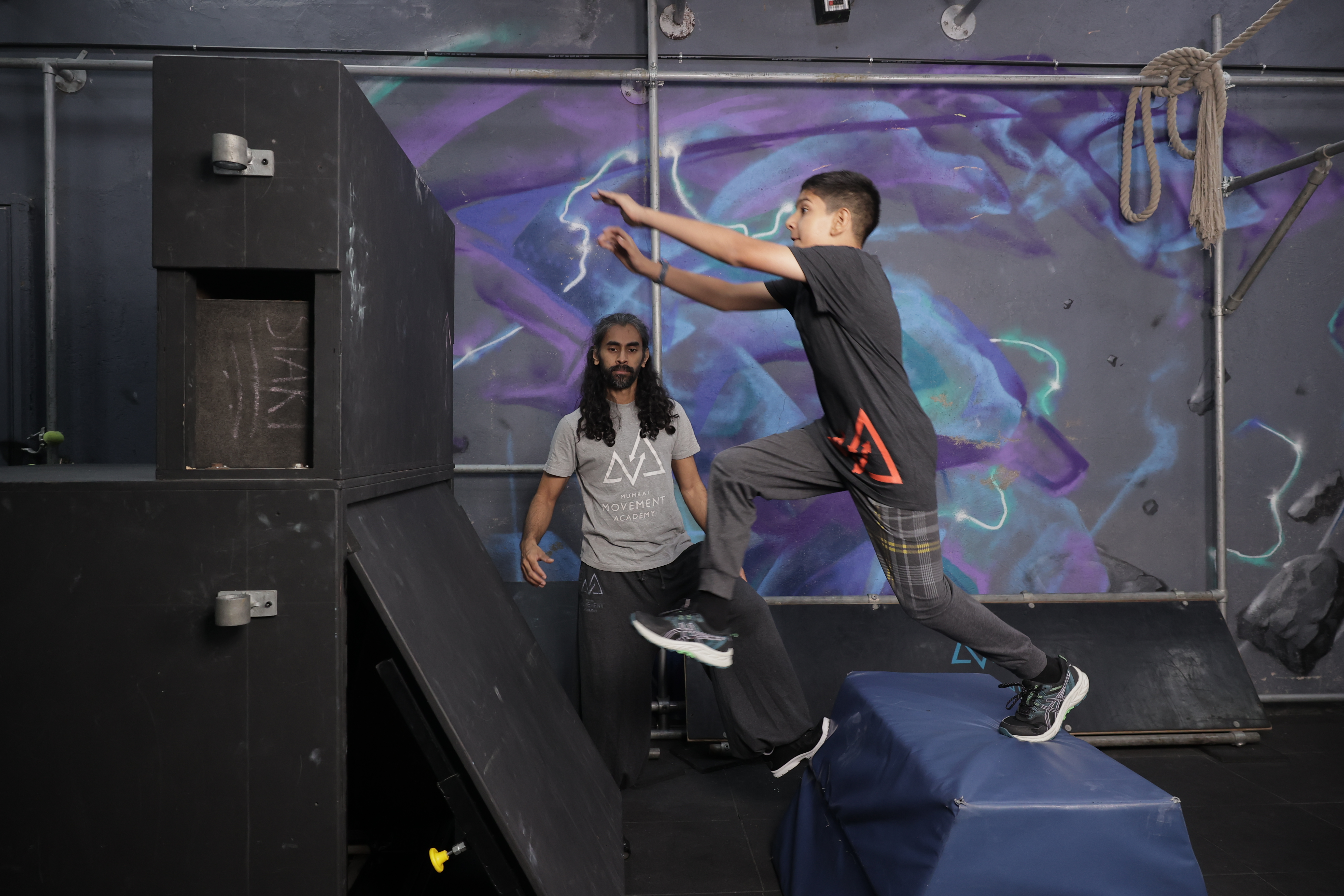 A coach guiding a student through a parkour practice