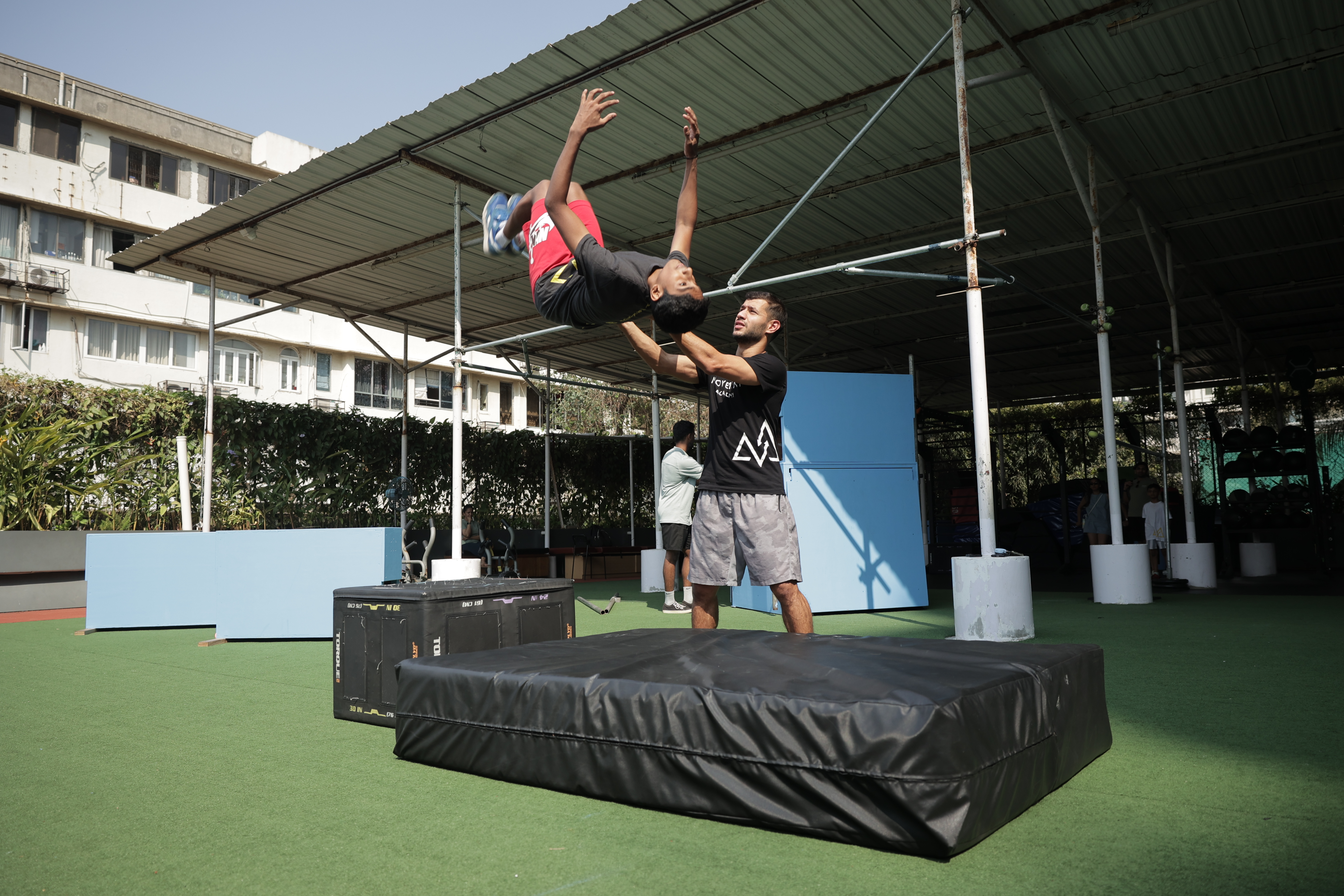 A coach spotting a young student during a parkour move